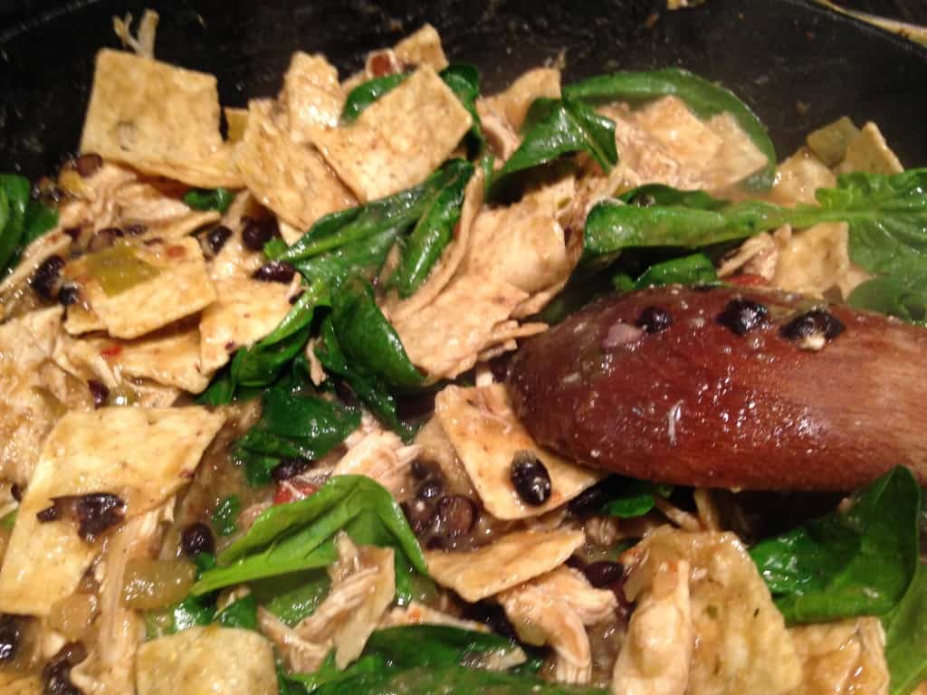 Stirring the tortilla chips and spinach into the salsa mixture.